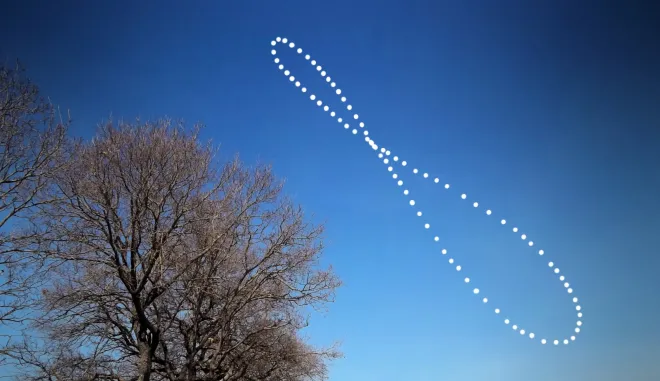 Le Soleil photographié à la même heure tout au long d'une année, traçant un analemme en forme de huit au-dessus d'arbres nus et d'un ciel bleu.