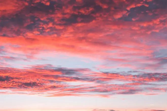 Des nuages rouges et roses éclairés par-dessous après le coucher du soleil.
